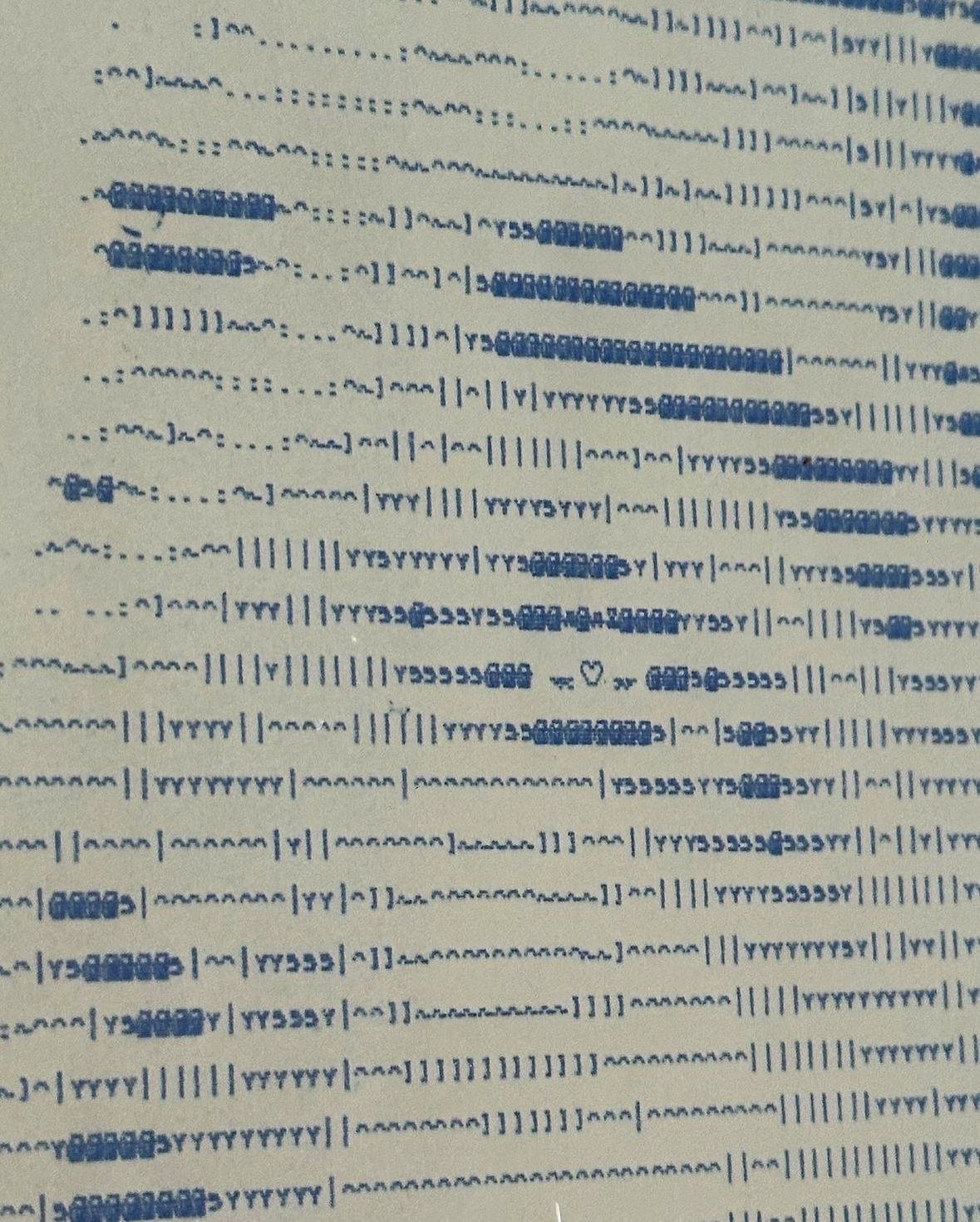 Macro detail of AWAITING INPUT by CHARACTERS — close-up of ASCII character grid on dot-matrix paper showing the eye and face of a reclined nude figure rendered in monospaced characters. 2024.