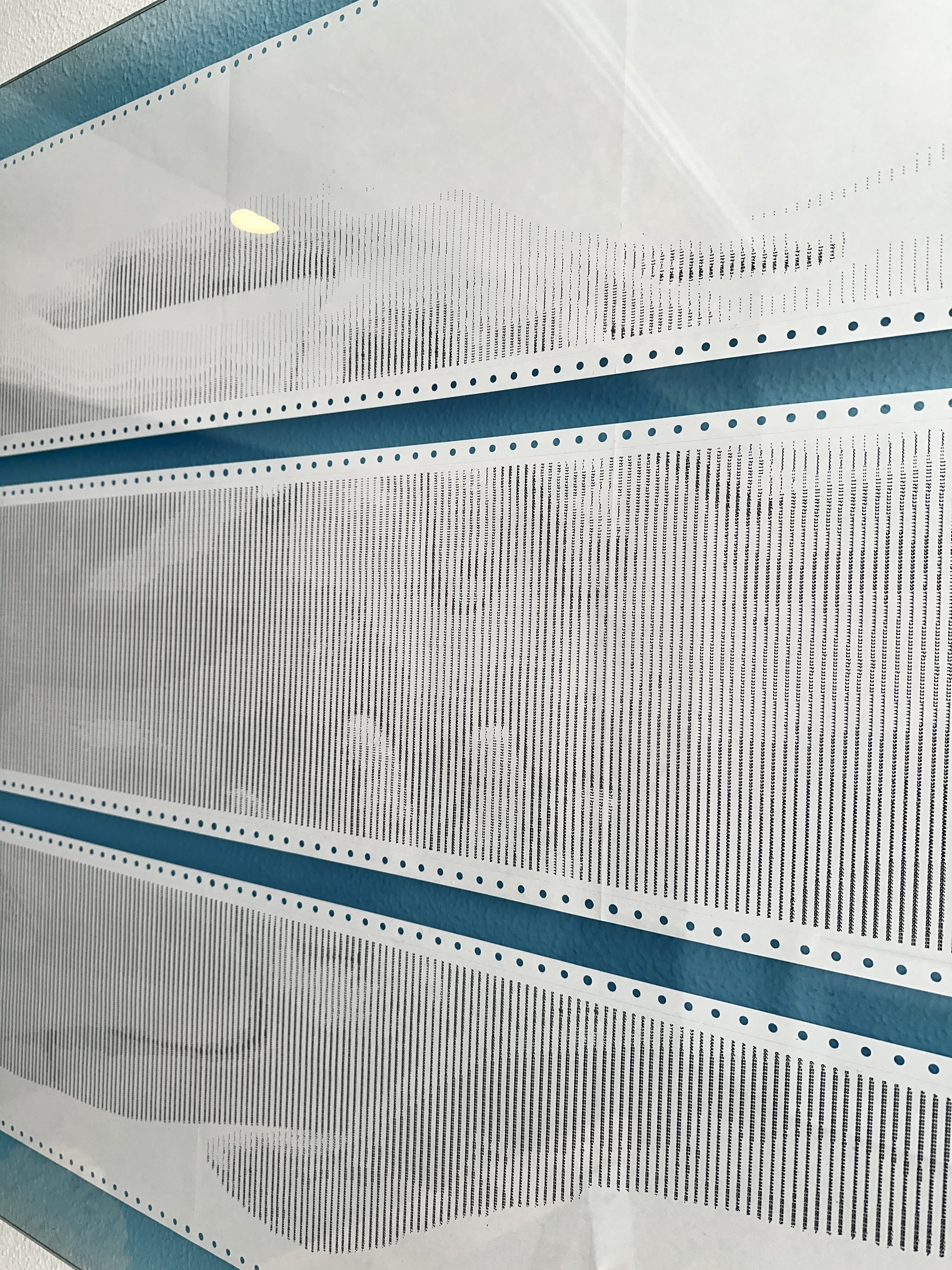 BODY.QUEUE by CHARACTERS — close-up of ASCII character grid on dot-matrix paper showing two male figures interlocked in a huddle-like pose, rendered in monospaced characters. Impact printing on deadstock continuous-feed stock.