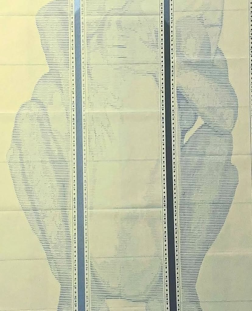 SAFE MODE by CHARACTERS — close-up of ASCII character grid on dot-matrix paper, Yellow colorway, showing two male figures in full embrace rendered in monospaced characters. Impact printing on deadstock continuous-feed stock.